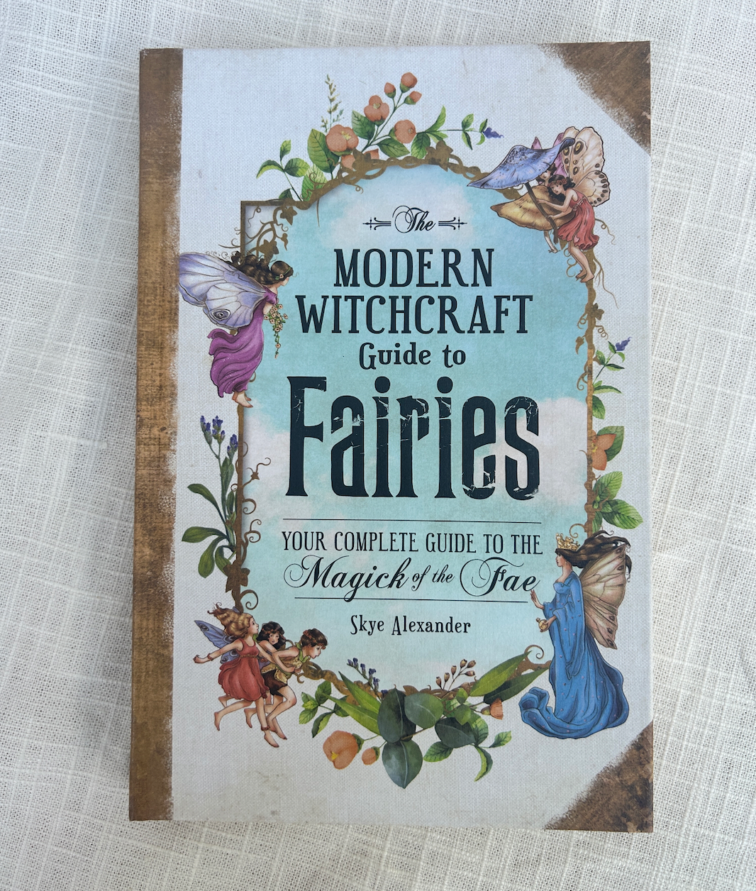 The cover of Spellcrafter’s The Modern Witchcraft Guide To Fairies shows vibrant fairy and flower art, highlighting themes of fairy witchcraft on a decorative background.