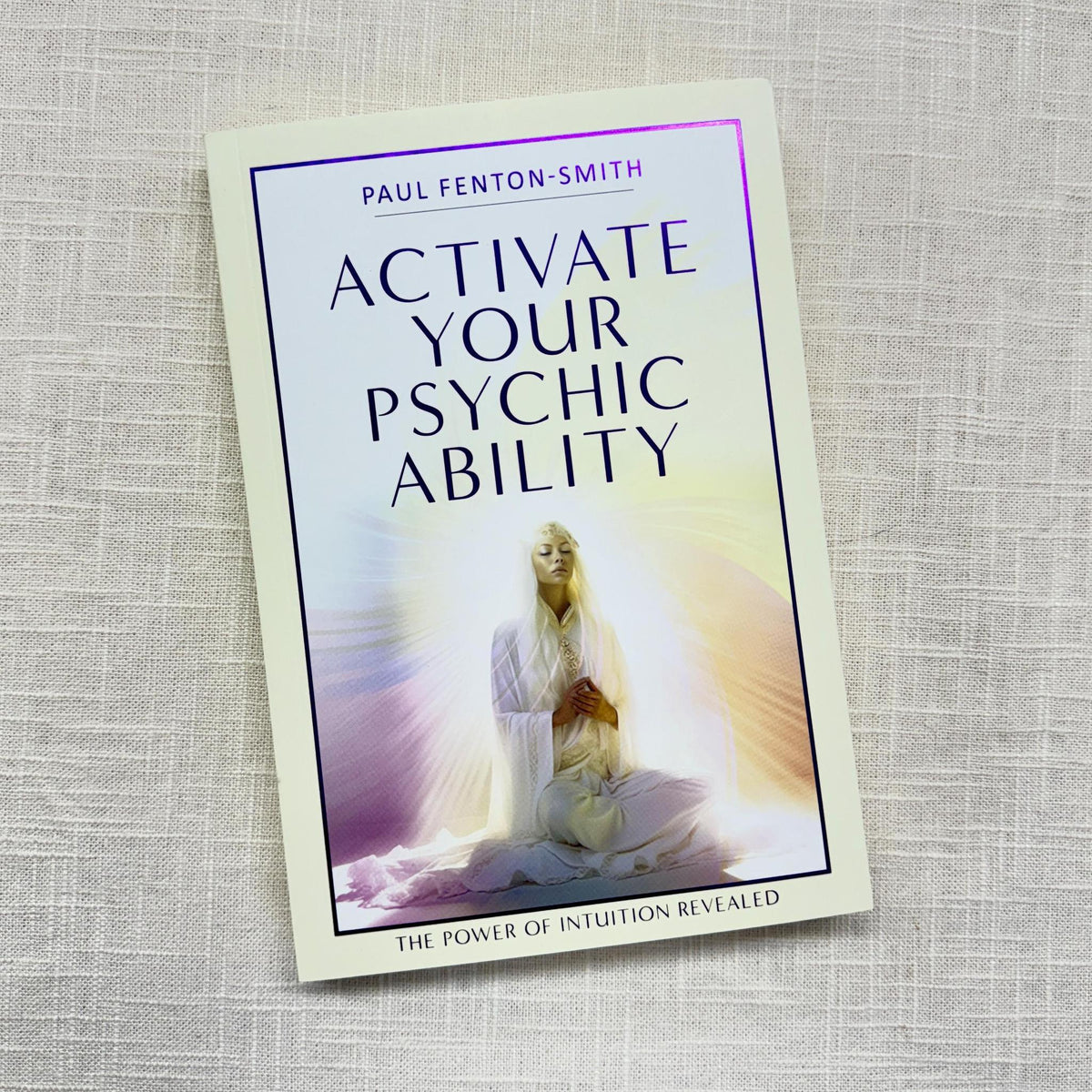 The Spellcrafter book "Activate Your Psychic Availability" rests on a light textured surface, featuring a meditative figure and soft purple and gold rays that suggest intuitive guidance.