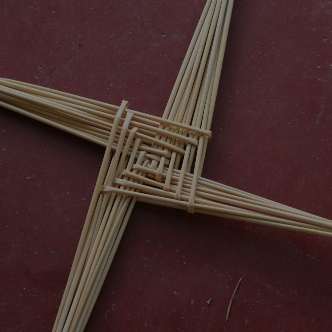 A woven star of light wood lies on a reddish-brown surface, its sticks forming...