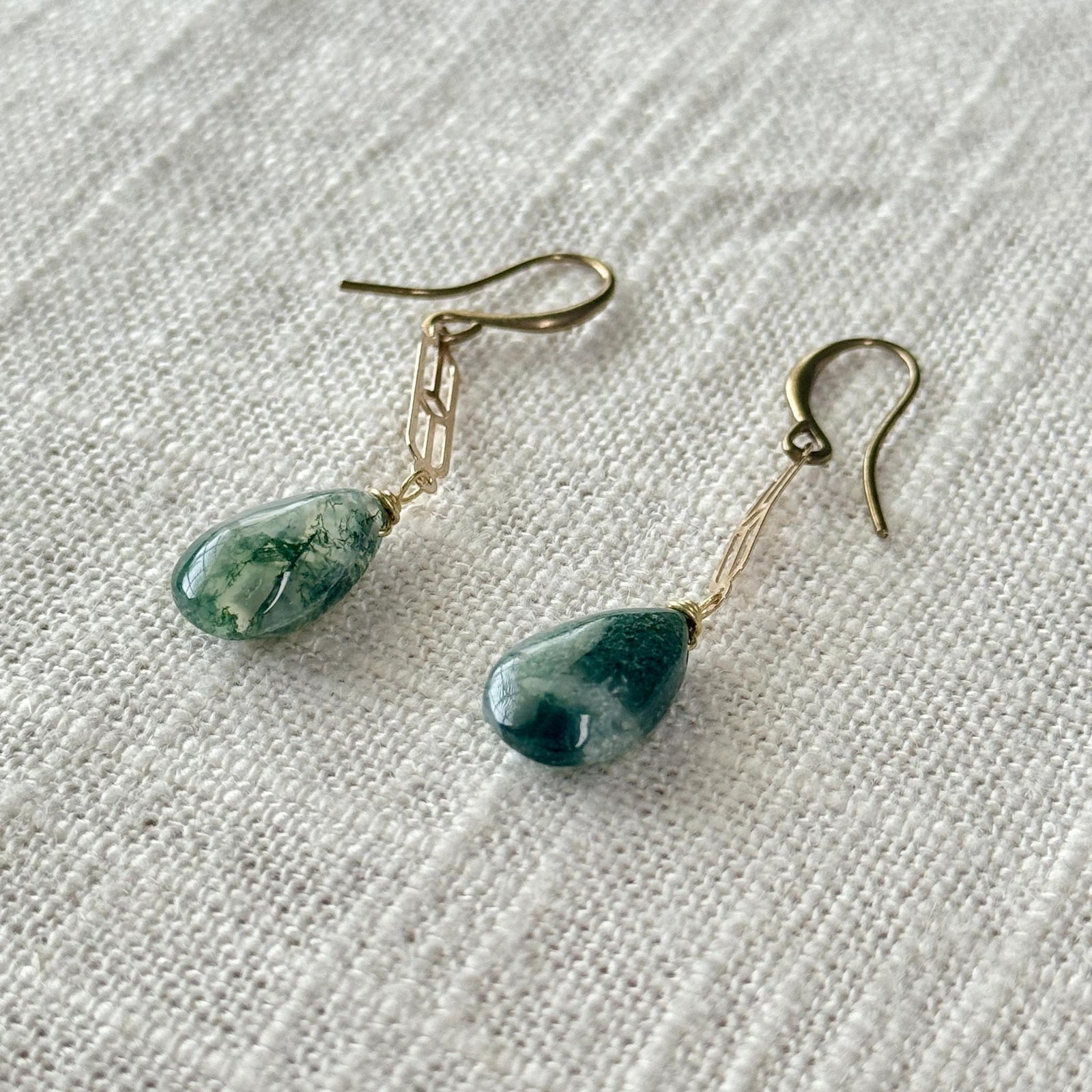 Spellcrafter's Moss Agate Chain Earrings feature green marbled Moss Agate teardrops on gold hooks,...