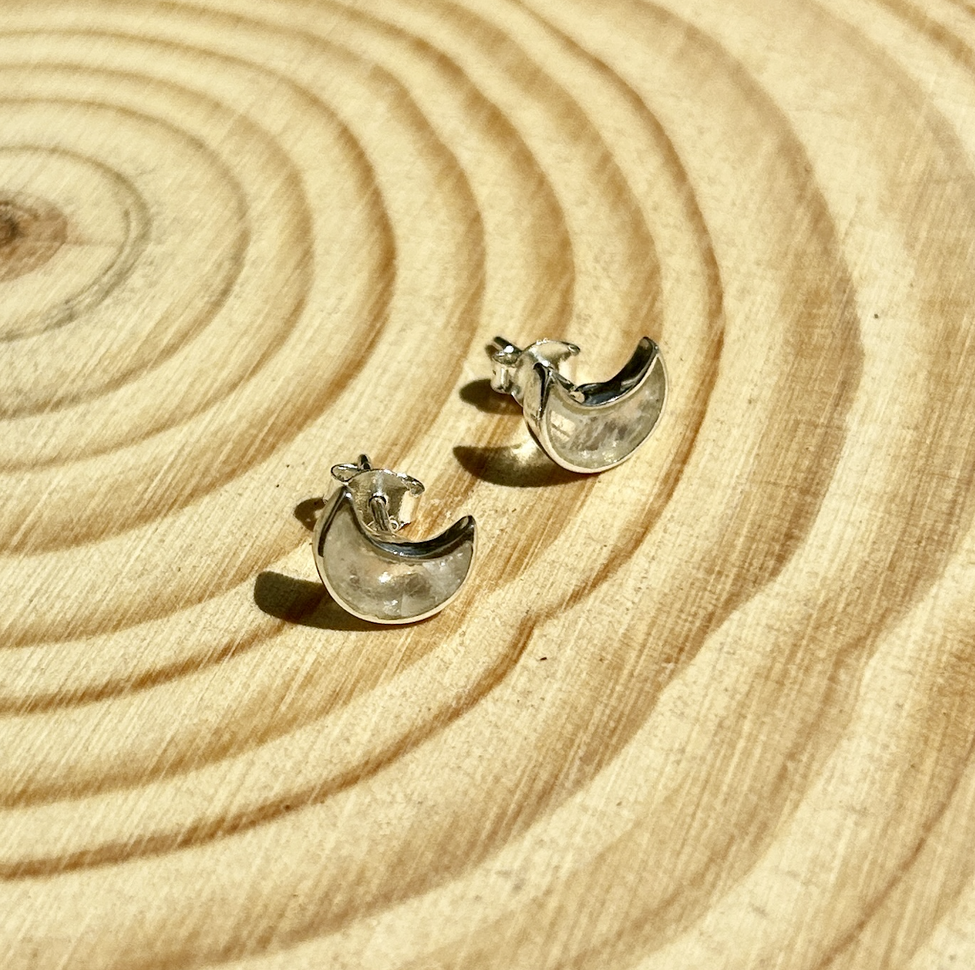 A pair of Spellcrafter Rainbow Moonstone Butterfly Sterling Silver Stud Earrings displayed on a...