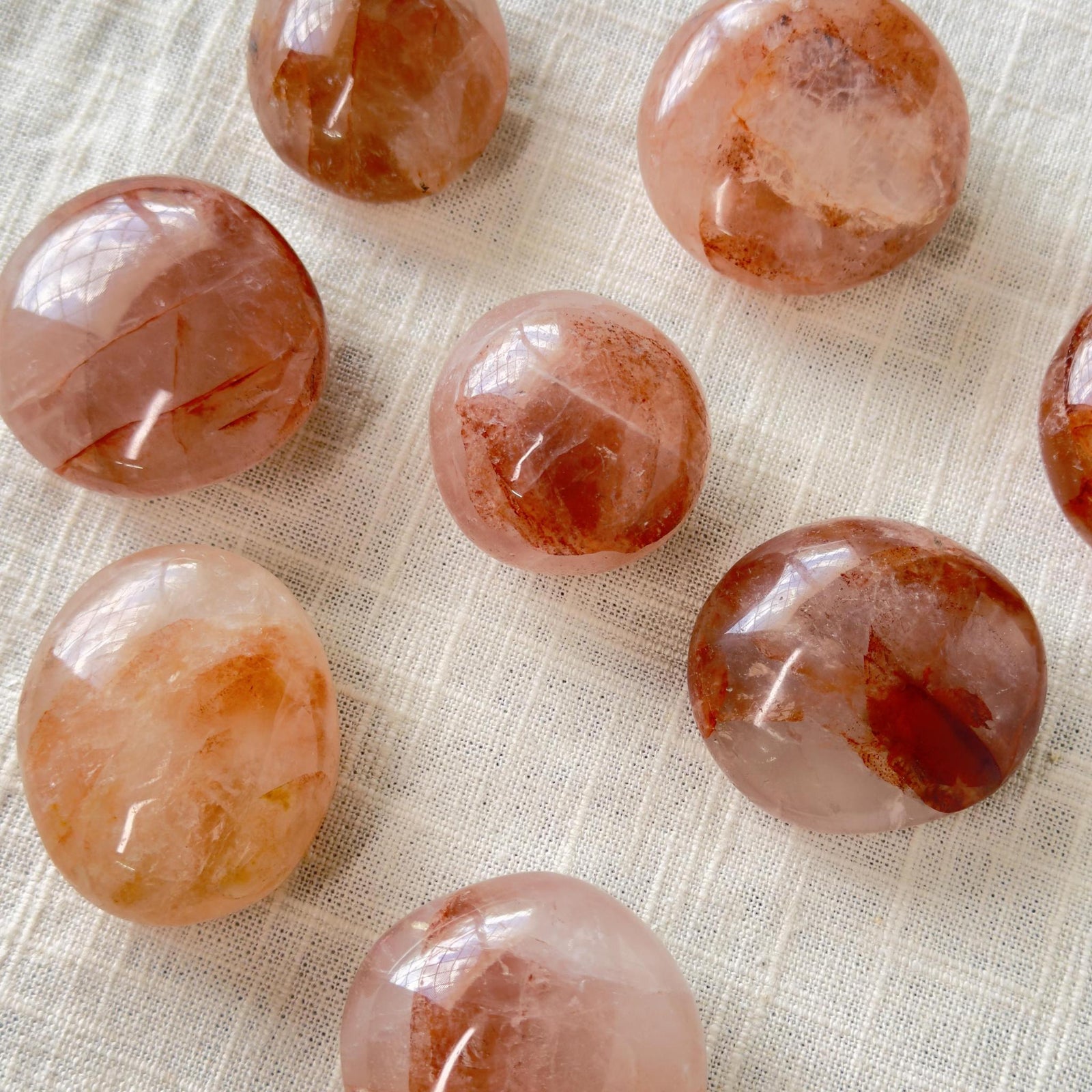 Nine Spellcrafter Fire Quartz Palm Stones, featuring polished round shapes with reddish-brown and translucent...