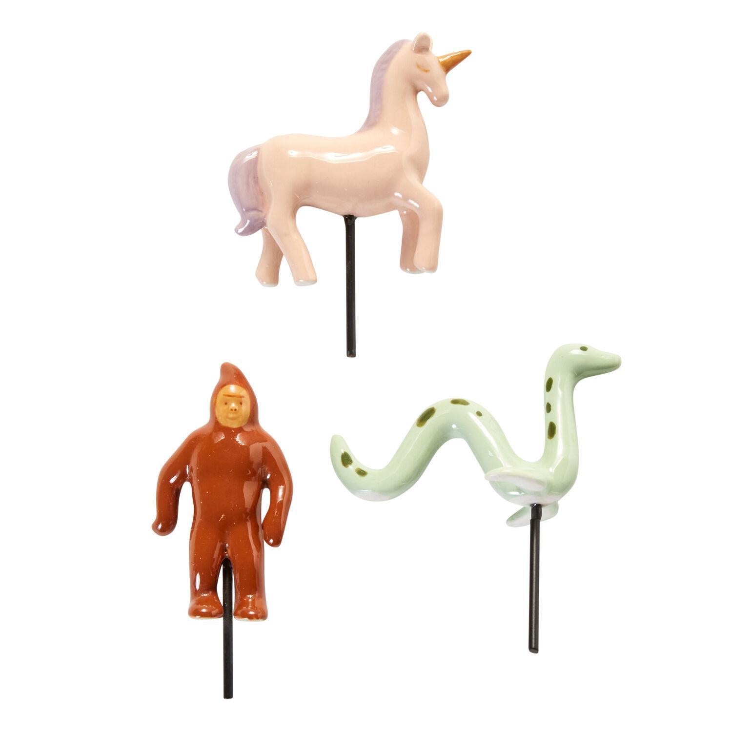 The Spellcrafter Mythical Creature Ceramic Plant Stake set includes a pink unicorn with a...