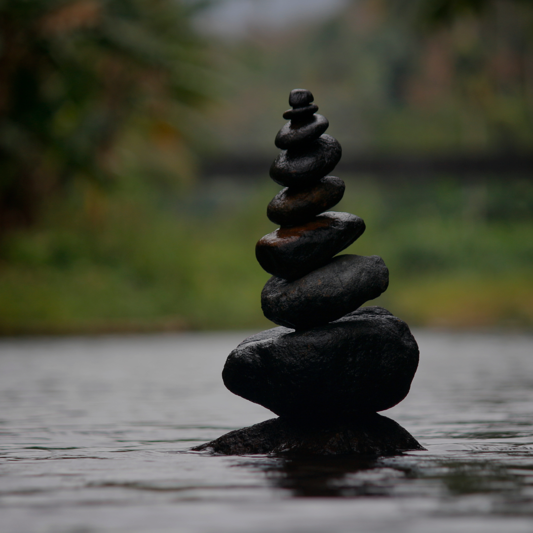 A stack of smooth, dark stones balances in shallow water, evoking meditative calm—just like...