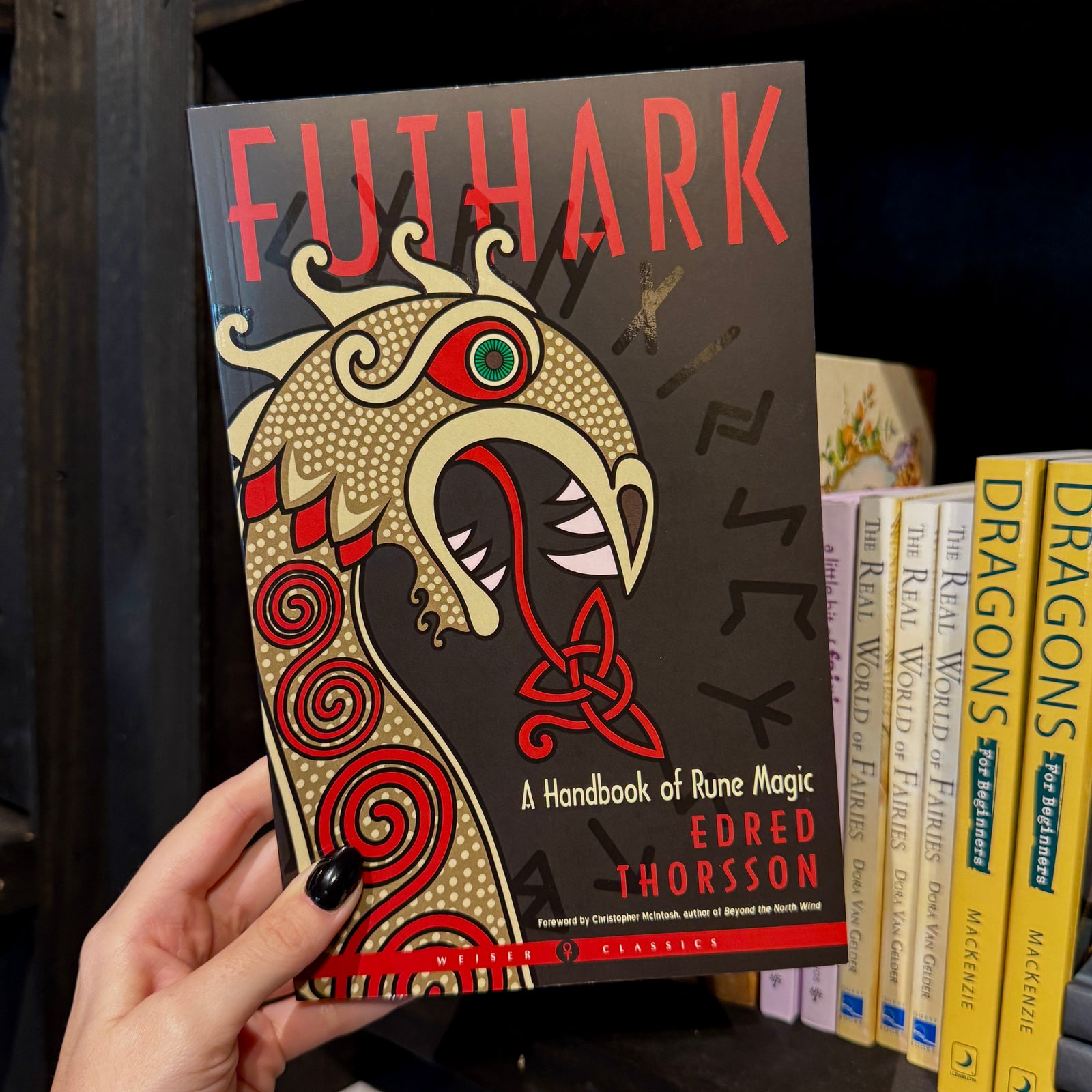 A hand holds Futhark by Spellcrafter, its cover showing a stylized Viking dragon head...
