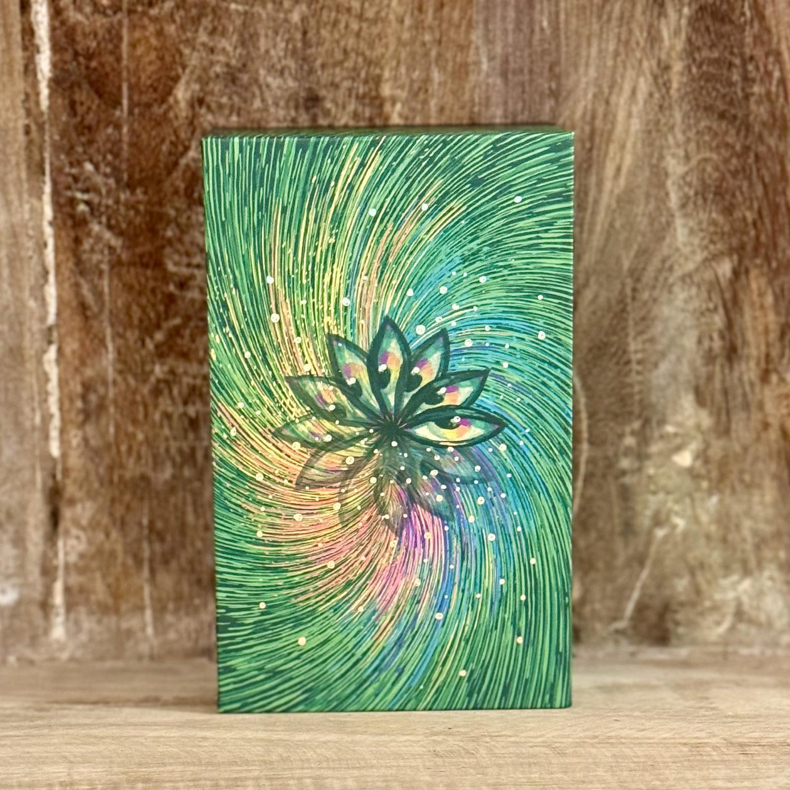 A rectangular object with a cover featuring swirling green, yellow, and pink abstract patterns...