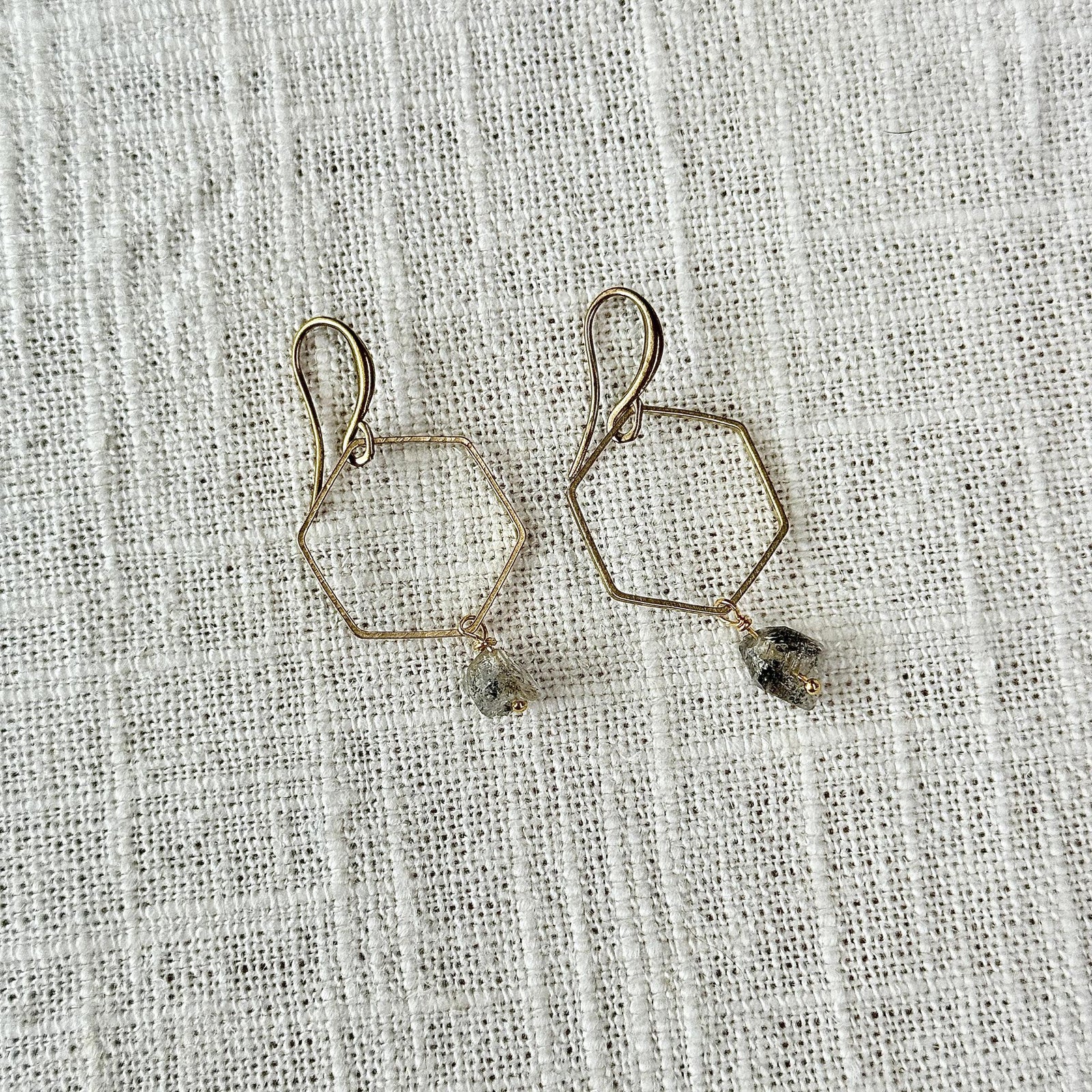Spellcrafter’s Herkimer Hexagon Earrings feature gold hexagon wire shapes adorned with small faceted Herkimer...